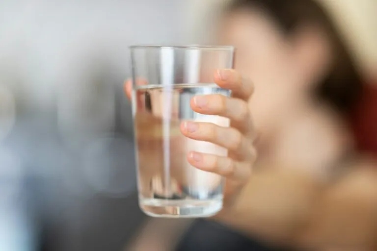Mână care ține un pahar cu apă, remediu clasic pentru sughiț
