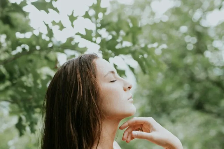 Femeie cu ochii închiși care respiră calm în natură
