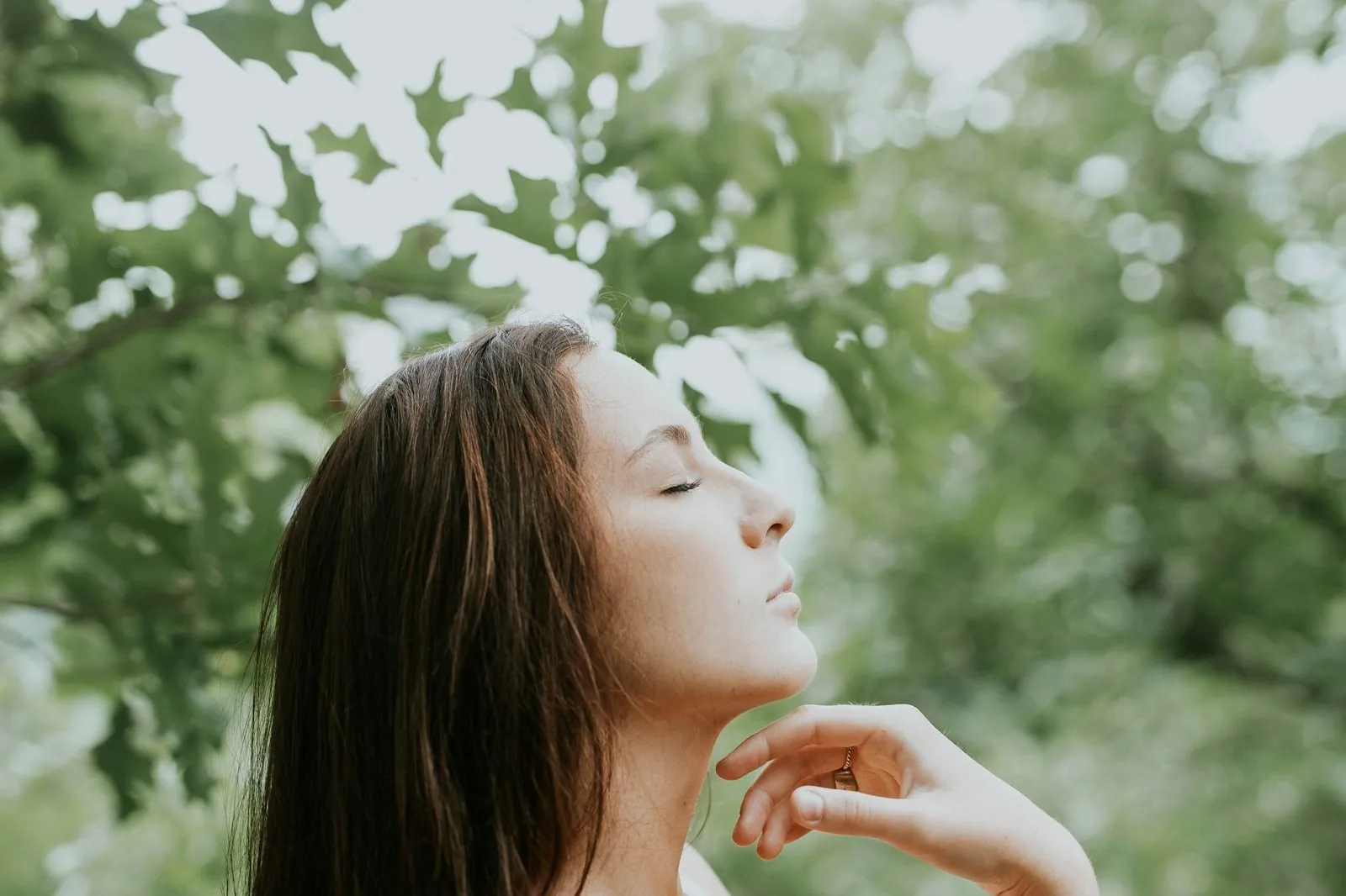 Femeie cu ochii închiși care respiră calm în natură