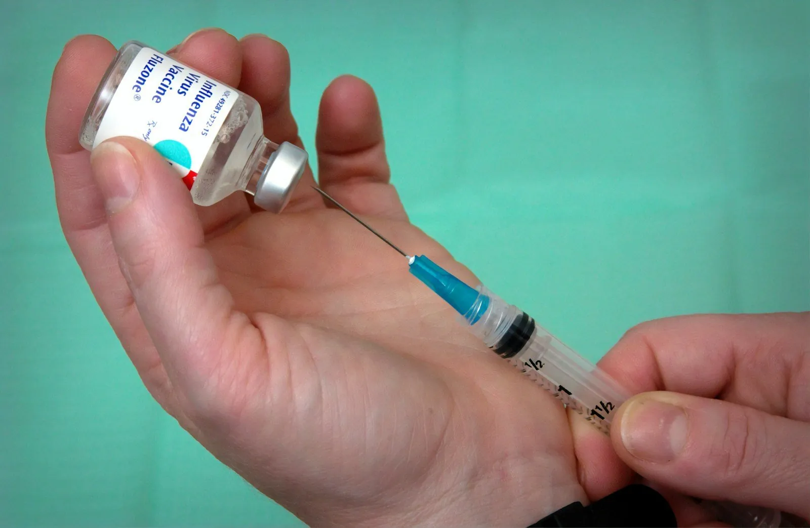 Asistentă care pregătește o doză de vaccin antigripal cu seringa
